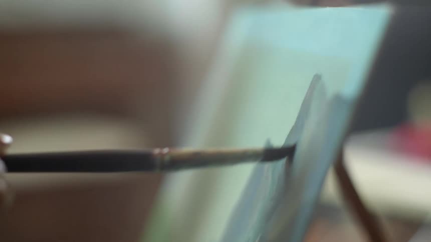 A person paints on an easel