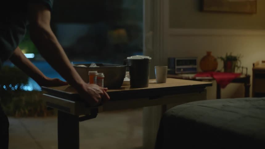 A man pushes a tray towards the bed