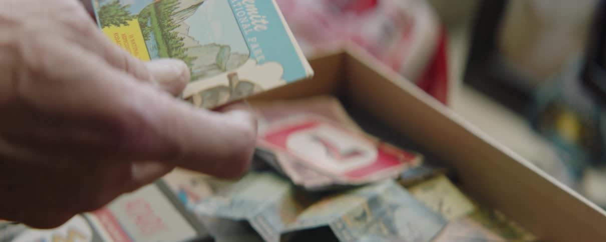 Man rummaging on a drawer filled with vintage items picks up a postcard
