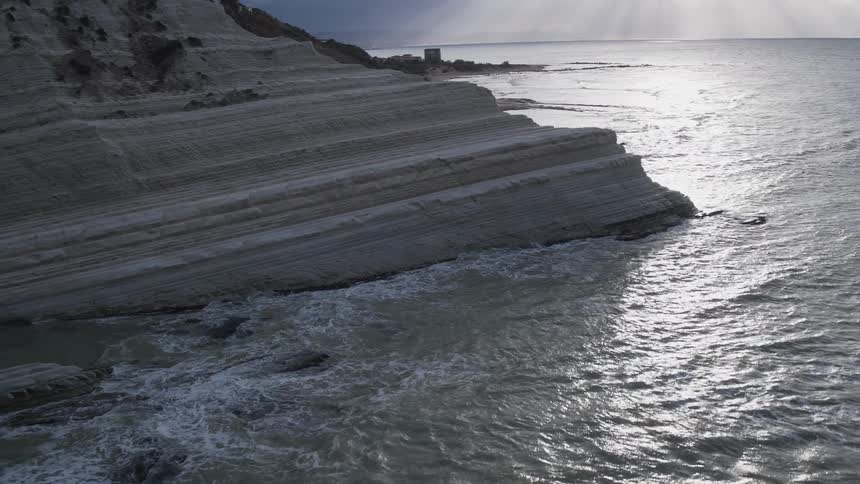 White cliffs are battered by waves under a cloudy day