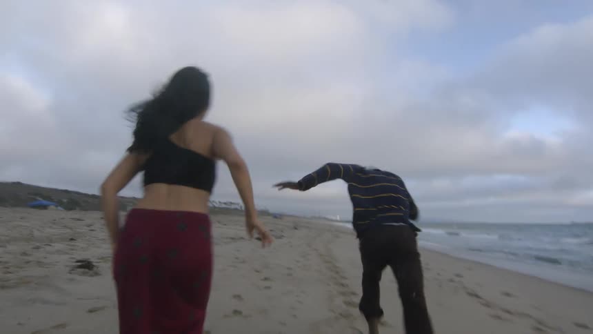 A man and woman while running after each other on the beach