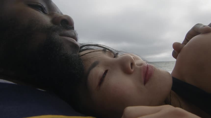 Young couple cuddling on the sand beach next to the ocean at evening