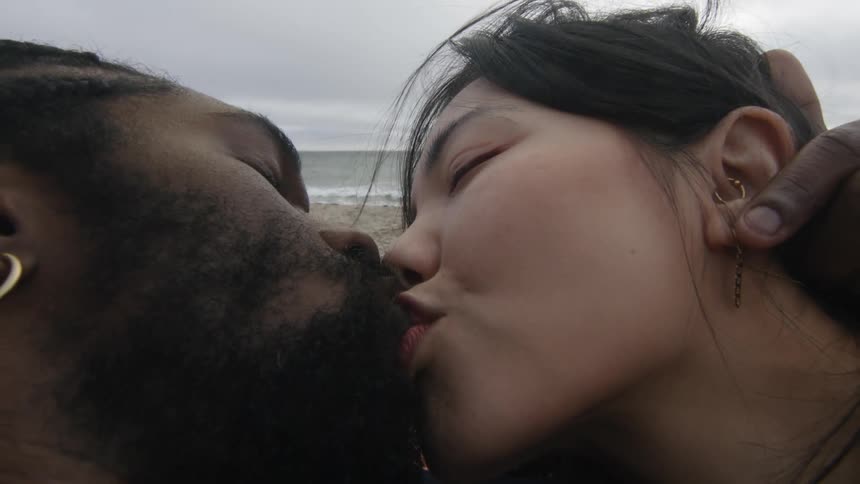 A couple make out while lying on the beach