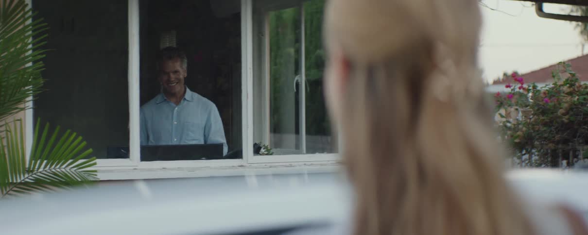 Man and woman are smiling to each other through a window