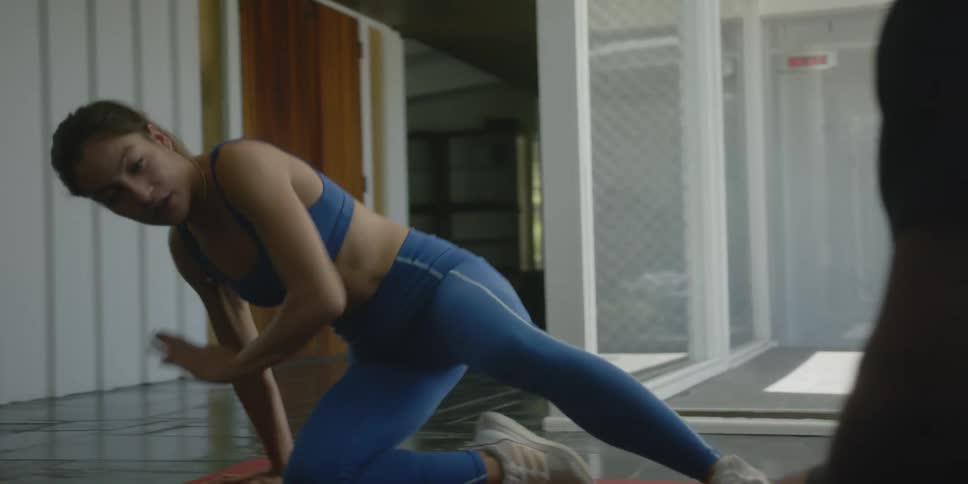 Woman talks to man while demonstrating proper exercise form