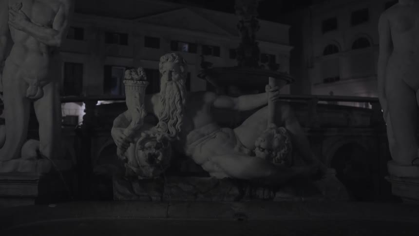 Some famous statues are outside on a lawn in front of some buildings