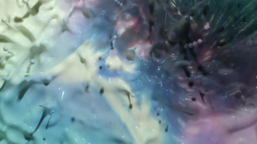 Pink and blue reflect in a moving liquid as it splashes