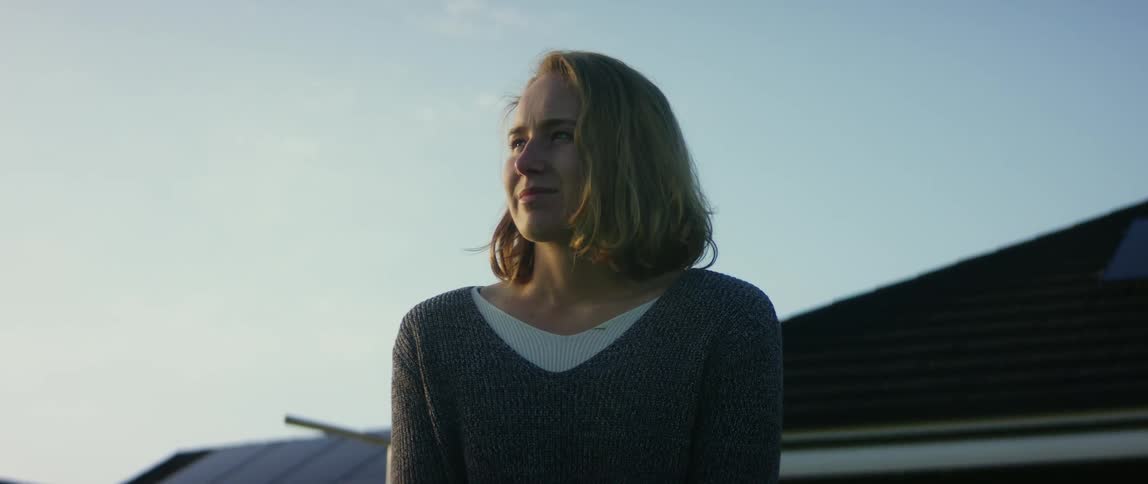 Blonde woman wearing gray sweater looks around in the coutryside