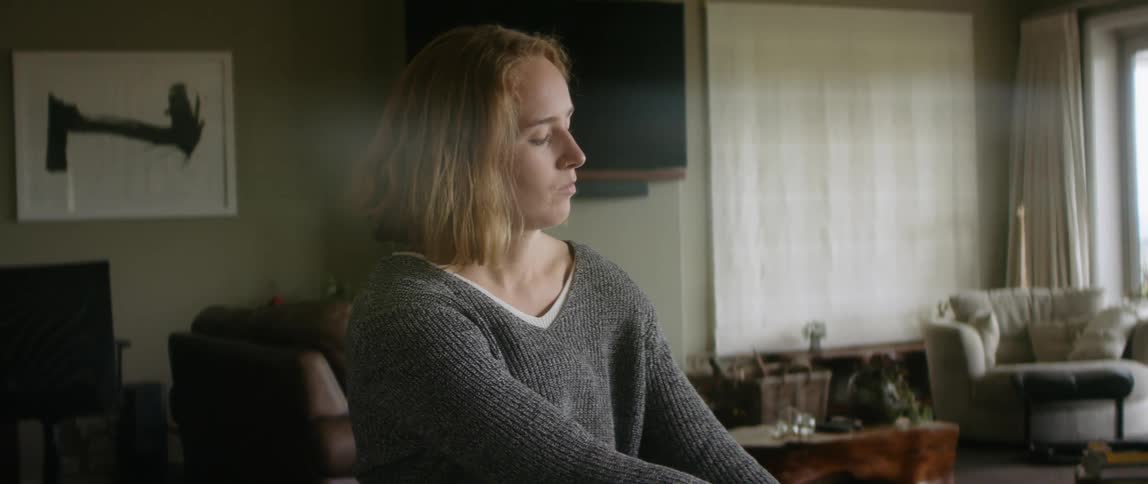 Woman sitting in wheelchair in living room puts on a shoe