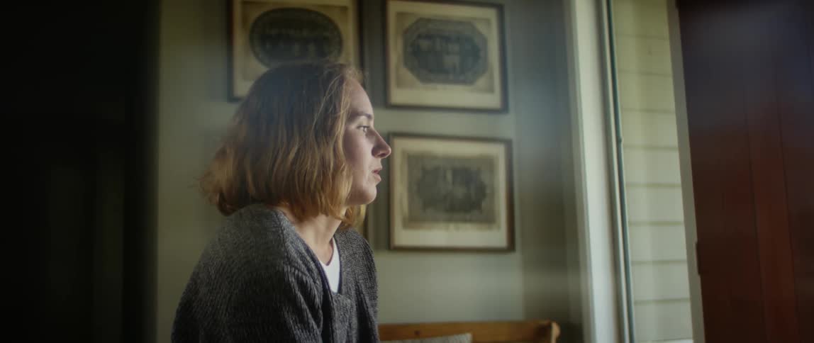 Blonde female wheelchair user wearing gray sweater looks out window