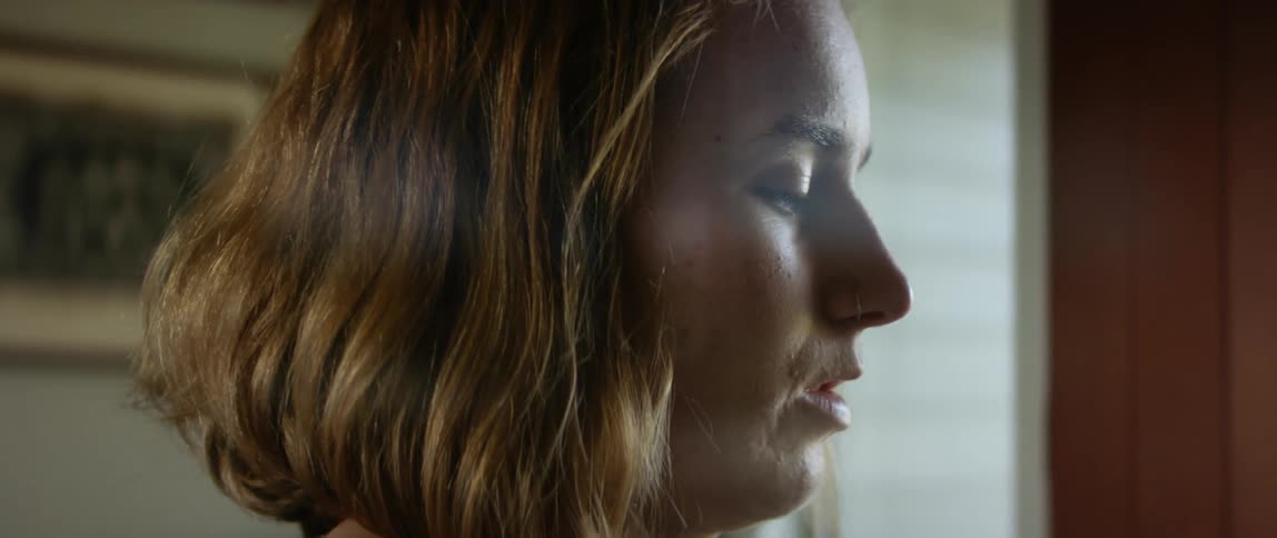 Light shines on the face of a teenage girl who appears to be in deep thought