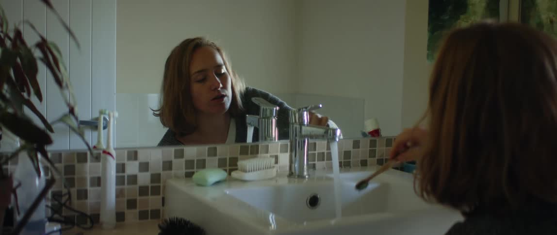 A woman is brushing her teeth in a bathroom