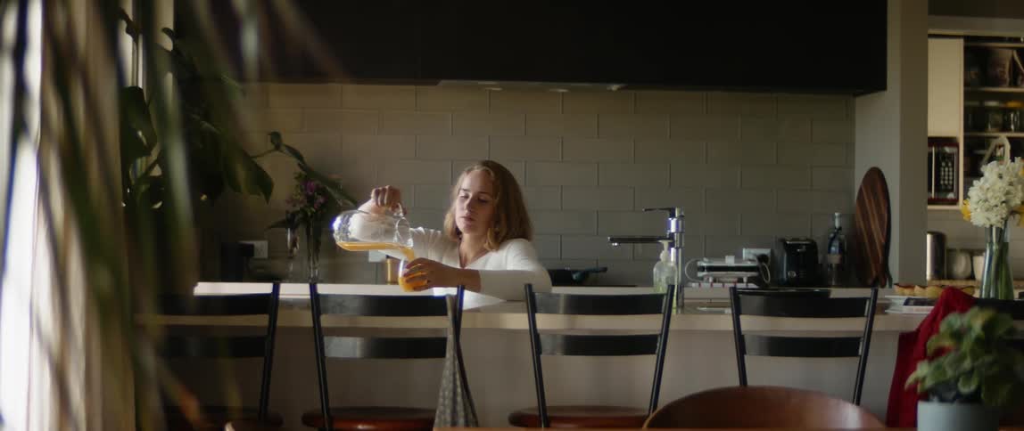 A woman is pouring a glass of juice in a kitchen