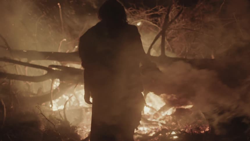 A man walks toward a large fire
