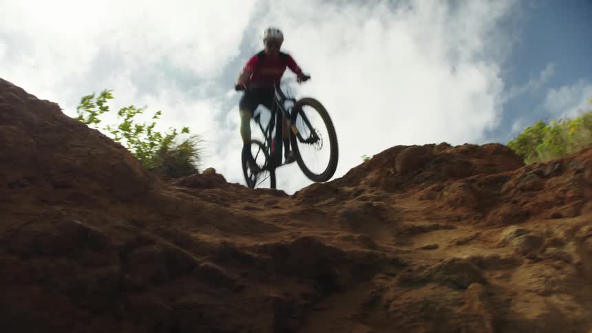A person mountain bikes down a steep dirt hill