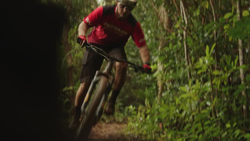 A man riding a mountain bike on a dirt path in a forest