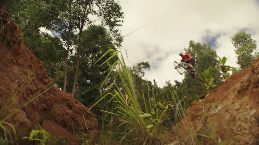 A cyclist jumps over a creek in the woods