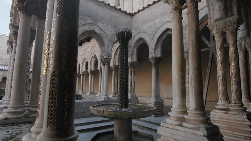 A water fountain is surrounded by the columns of a building