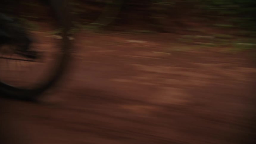 A person is dirt biking through a wooded area