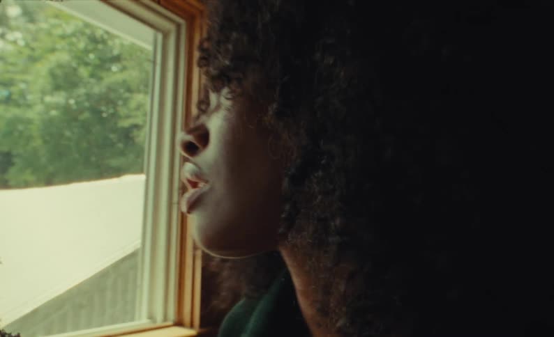 Annoyed black woman standing next to a window complaining about something