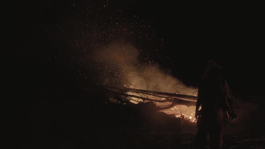 A man walks toward a burning brush pile