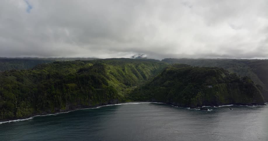 A mountainous coastline covered in vegetation on a cloudy day