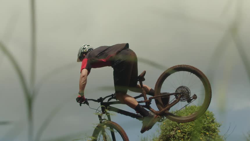 Cyclist takes jump on hill slope under an overcast sky