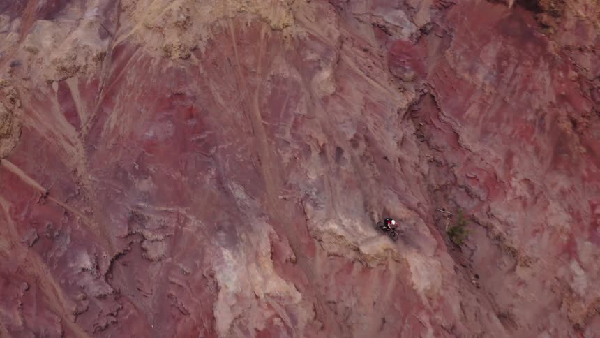 A person is riding a dirt bike down a mountainous area