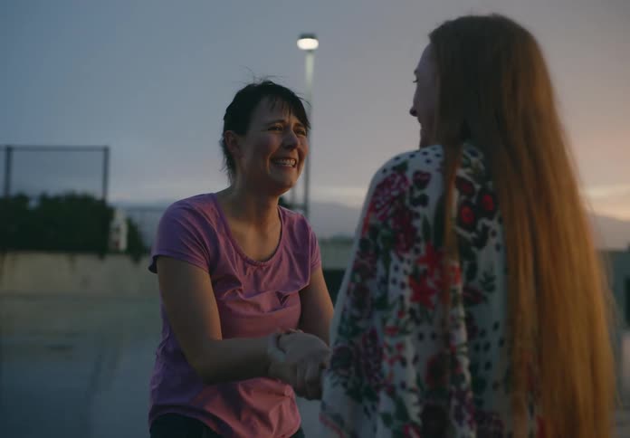 Two women running towards each other hugging laughing and crying of joy