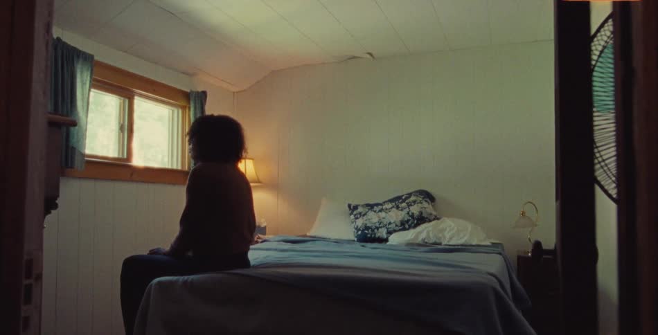 Two people sit on a bed together and one leaves