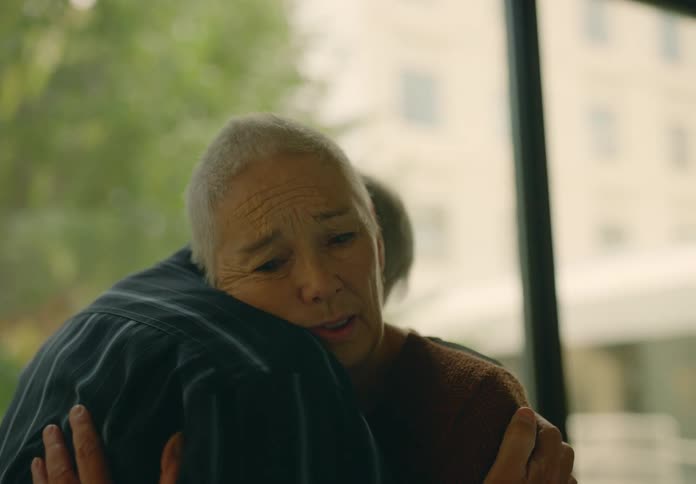Old man hugging an old woman while she has an anguished and sad look on her face