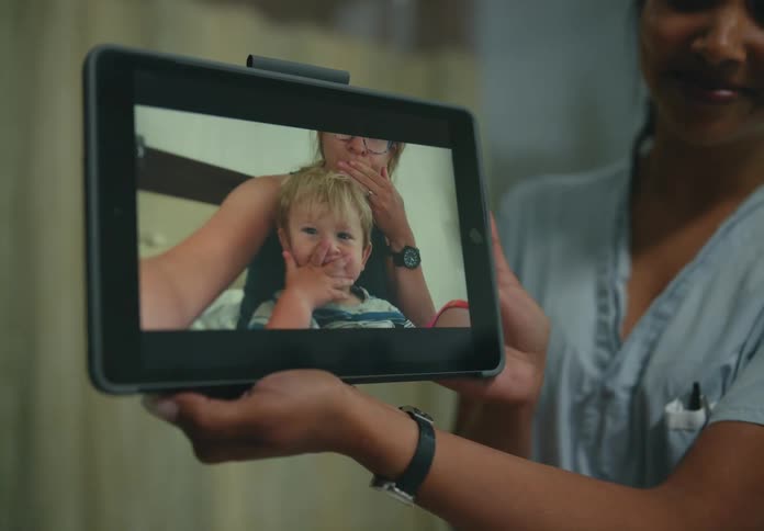 Family having a video call while the nurse is holding the tablet for the patient at the hospital