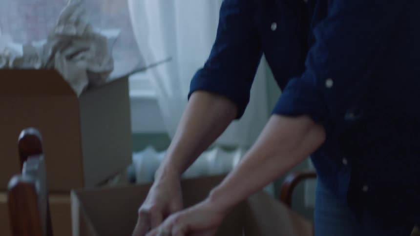 A woman is packing objects into boxes