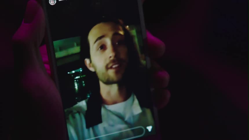 A person holds a phone and video chats with a man holding a bottle