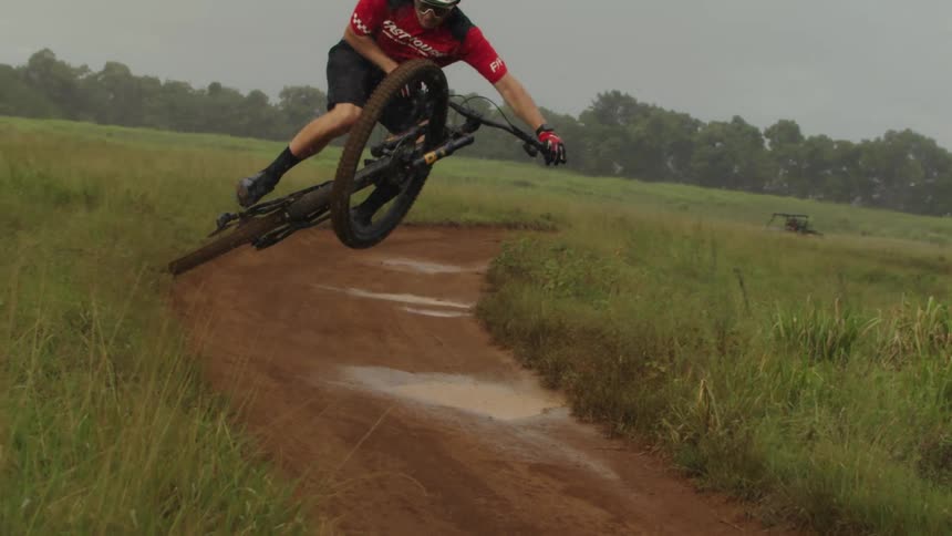 A man is doing stunts on his dirt bike while its raining