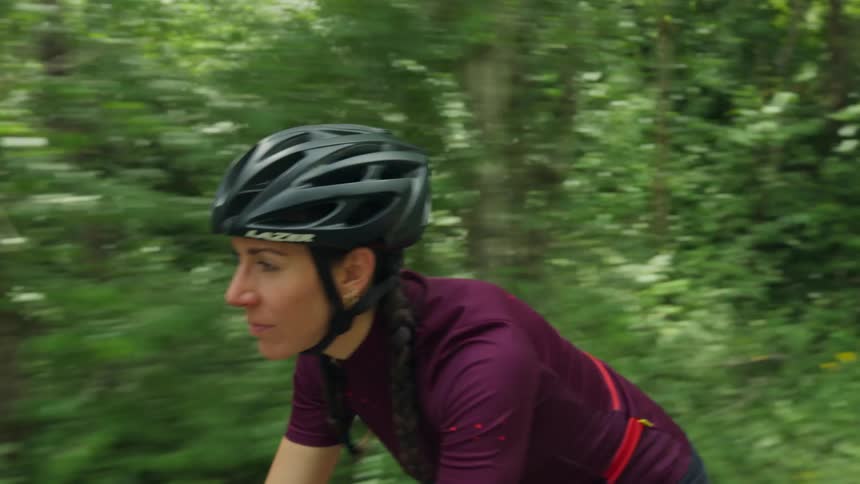 A cyclist rides past a forest