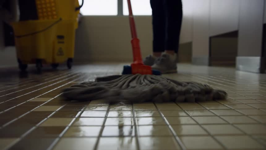 A person is mopping the floor in the bathroom in the middle of the day
