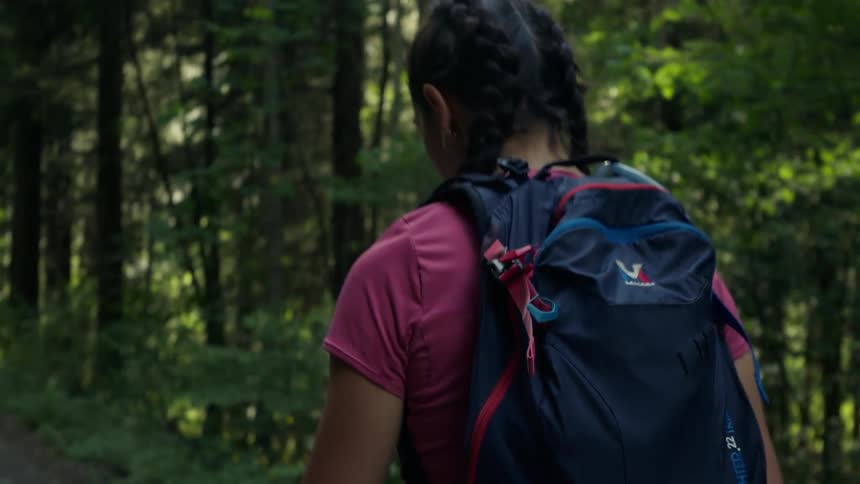 A young white woman is walking in the woods in the middle of the day