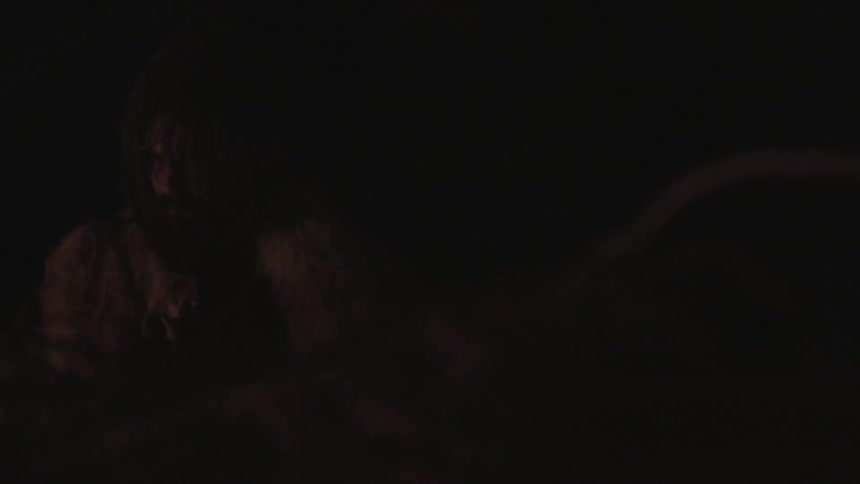 Bearded man sitting in a dark area outdoors