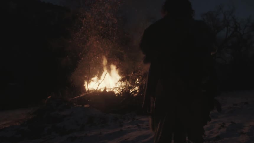 A man approaches a large bonfire
