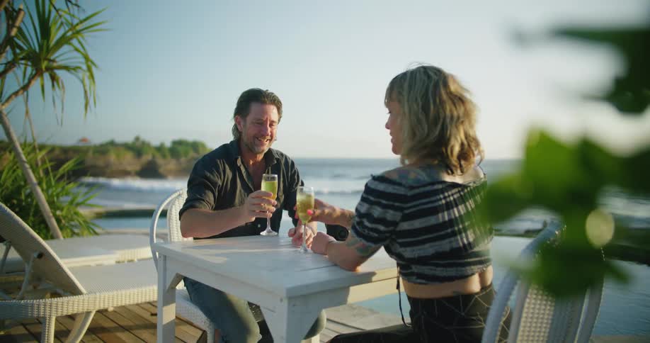 A couple have drinks on the beach