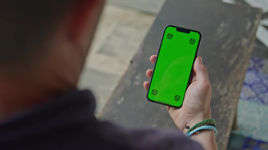 Man stares at a smartphone with a green replaceable screen he is holding on his hand