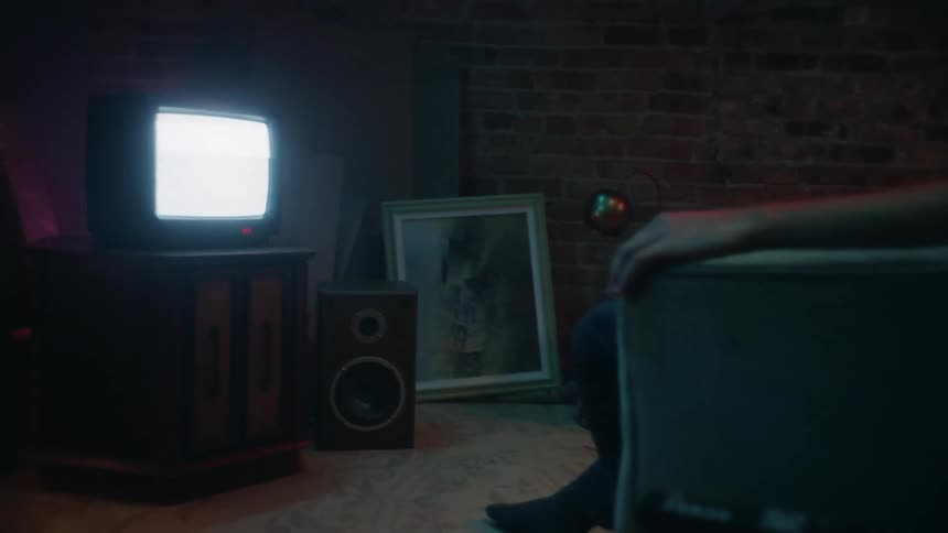 Person sits in living room watching old console television showing signal snow