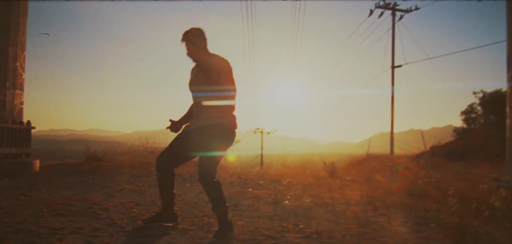 A man dances outdoors in the countryside in the evening