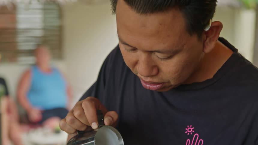 Barista carefully pours milk on a espresso cup