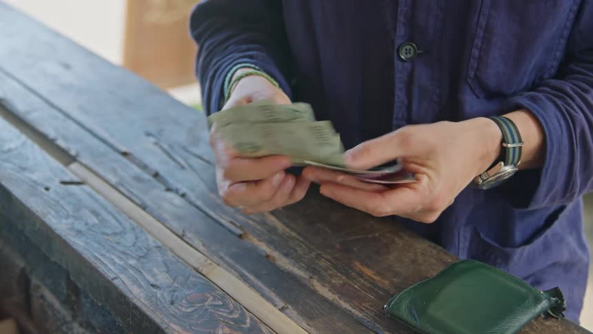 A man counts money to pay for an item at an outdoor stall
