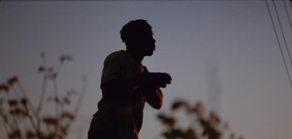 Silhouette of a young man dancing on the countryside at evening