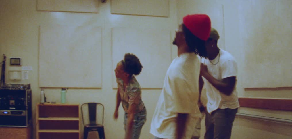 Group of happy people performing a choreographed dance in front of a mirror on a studio