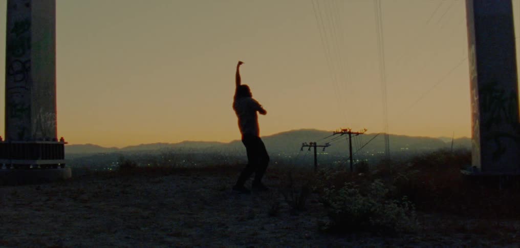 Male dancer dancing is silhouetted against the sky at dusk in the country