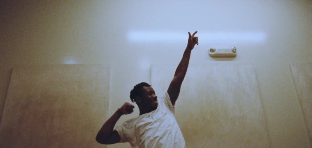 A man gestures upward while dancing indoors
